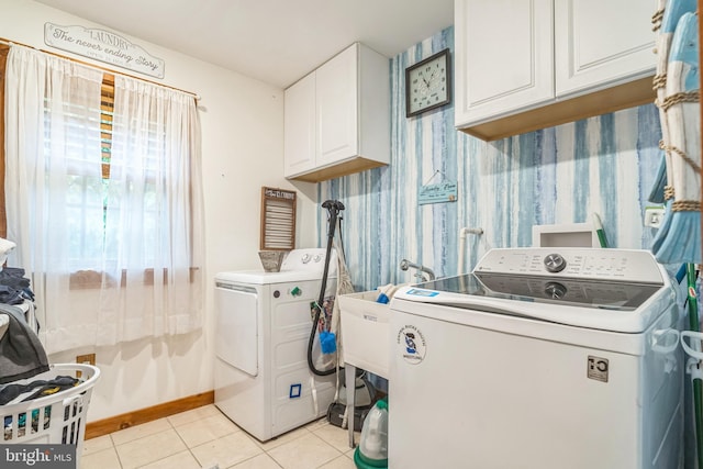 laundry area with separate washer and dryer, light tile patterned floors, and cabinets