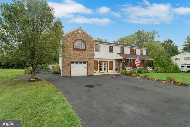 front facade featuring a front yard, a garage, and french doors