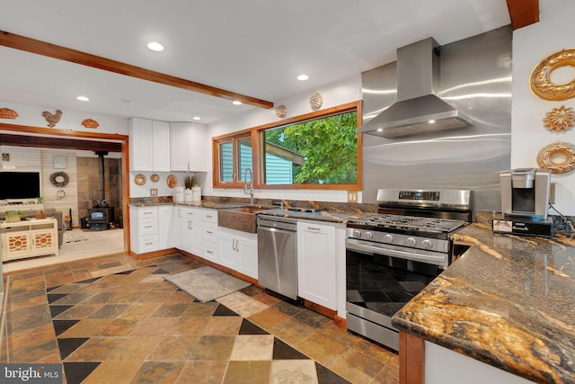 kitchen with white cabinets, sink, wall chimney range hood, appliances with stainless steel finishes, and dark stone countertops