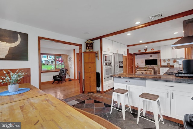 kitchen featuring extractor fan, white cabinetry, decorative backsplash, stainless steel appliances, and dark hardwood / wood-style flooring