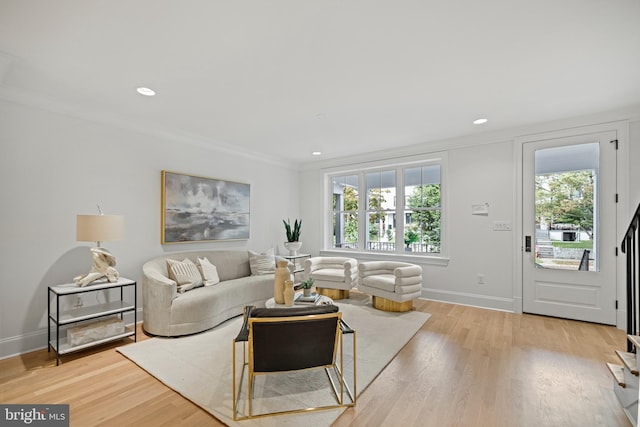 living room with light hardwood / wood-style floors, a wealth of natural light, and crown molding