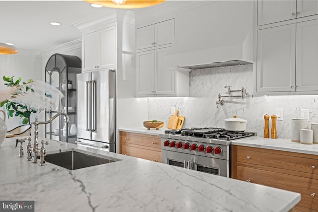 kitchen featuring white cabinetry, decorative backsplash, light stone countertops, and high end appliances