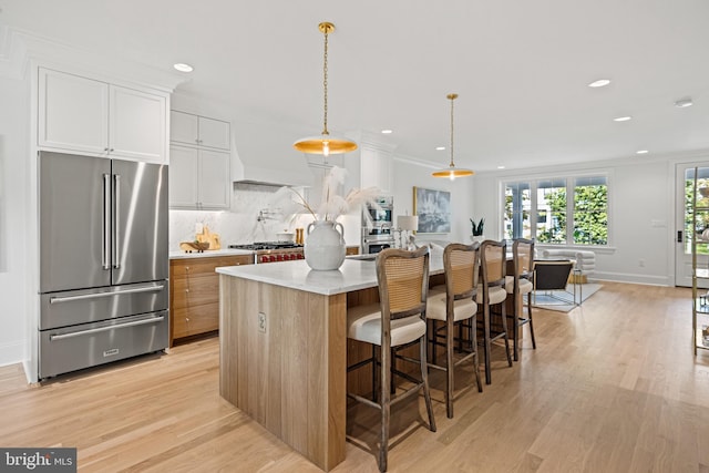 kitchen with light stone countertops, appliances with stainless steel finishes, light wood-type flooring, white cabinets, and a center island