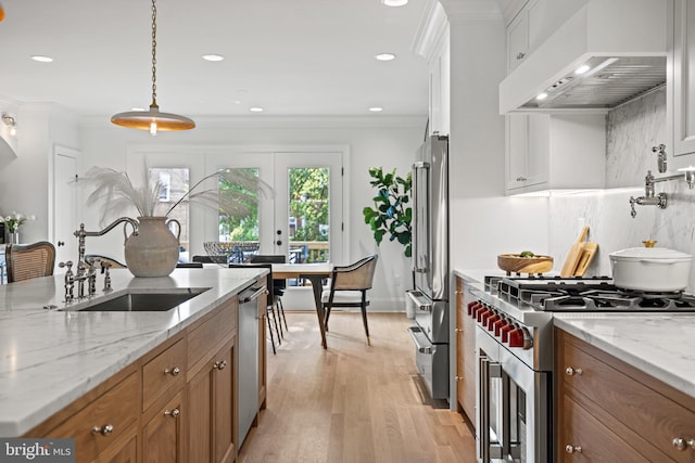 kitchen with ventilation hood, crown molding, light wood-type flooring, premium appliances, and white cabinetry