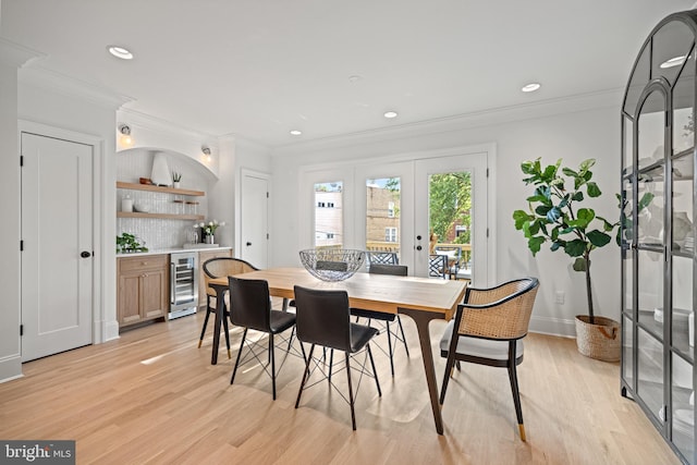 dining space featuring french doors, beverage cooler, light hardwood / wood-style floors, and ornamental molding