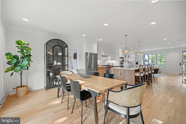 dining area featuring crown molding and light hardwood / wood-style flooring