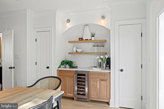 bar featuring crown molding, wine cooler, and light hardwood / wood-style flooring