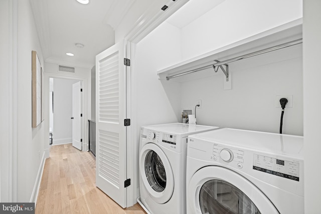 clothes washing area featuring washer and dryer, light hardwood / wood-style floors, and crown molding