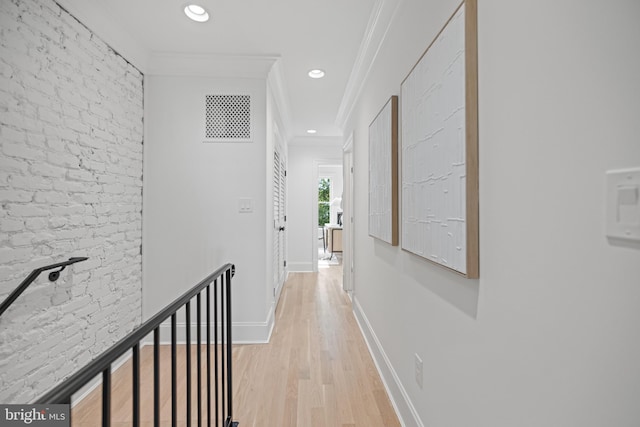 corridor with ornamental molding, brick wall, and light hardwood / wood-style flooring