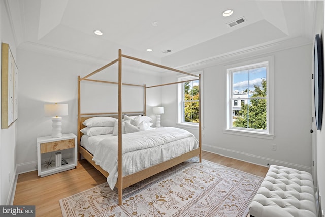 bedroom featuring a tray ceiling, crown molding, and light hardwood / wood-style floors