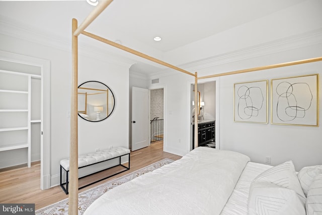 bedroom featuring connected bathroom, crown molding, and light hardwood / wood-style flooring