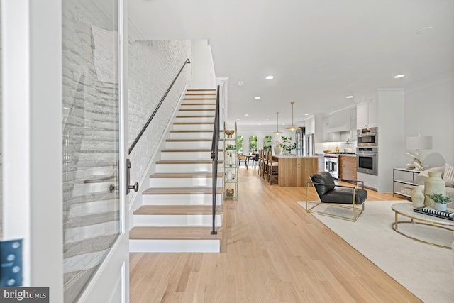 staircase with wood-type flooring and crown molding