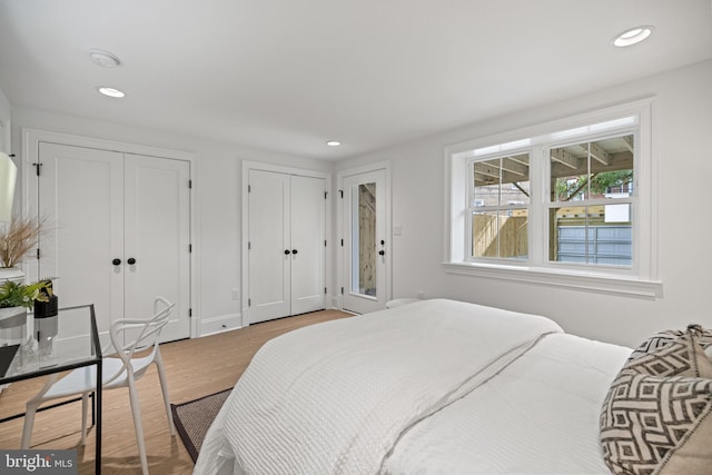 bedroom featuring light hardwood / wood-style floors and multiple closets