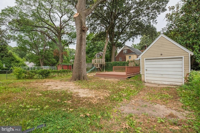 view of yard with a wooden deck, a garage, and an outbuilding