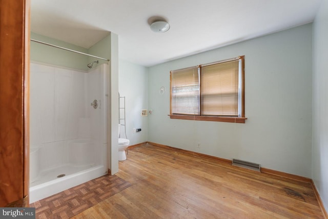 bathroom featuring toilet, walk in shower, and wood-type flooring