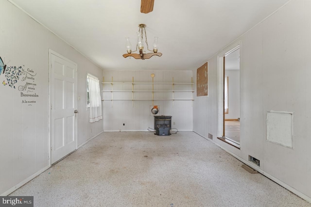 unfurnished dining area with an inviting chandelier, carpet floors, and a wood stove