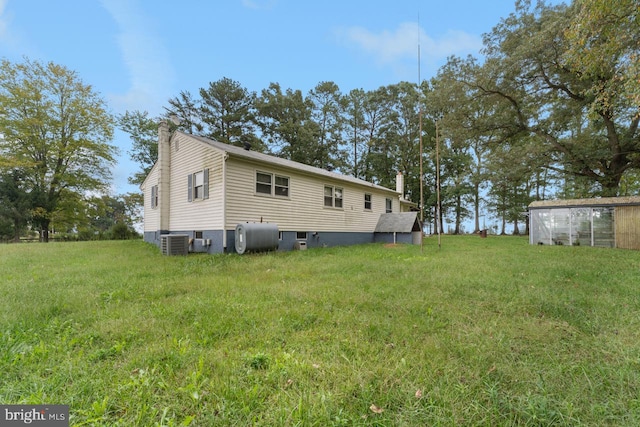 back of house with a yard and central AC