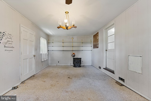 interior space featuring a notable chandelier, carpet flooring, and a wood stove