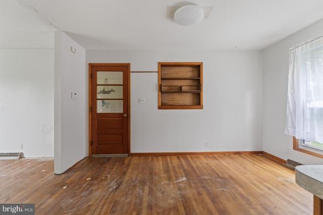 spare room with wood-type flooring and built in features