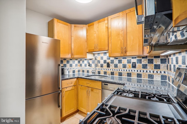 kitchen with sink, stainless steel fridge, dark stone counters, decorative backsplash, and light tile patterned flooring