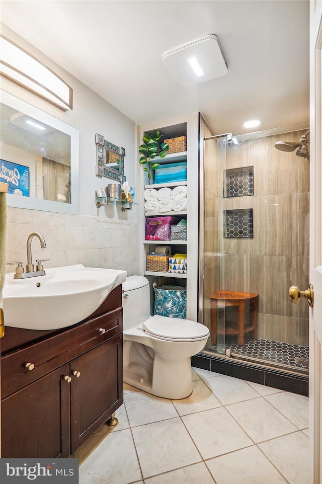 bathroom with walk in shower, tile patterned floors, toilet, vanity, and tile walls