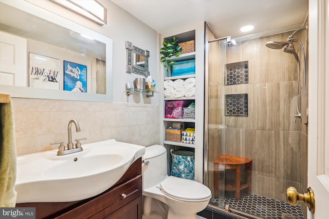 bathroom with walk in shower, vanity, tile walls, and toilet