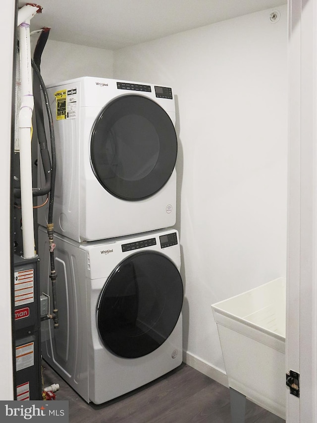 laundry room featuring stacked washer and dryer and dark hardwood / wood-style flooring