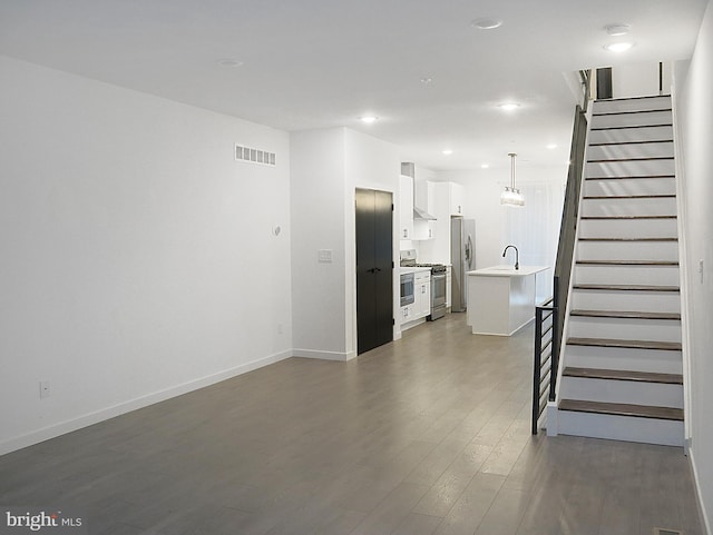 unfurnished living room featuring dark wood-type flooring and sink