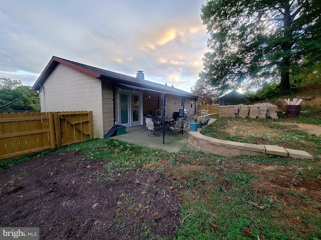 back house at dusk featuring a patio