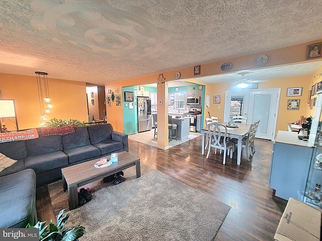 living room with ceiling fan, a textured ceiling, and dark hardwood / wood-style flooring