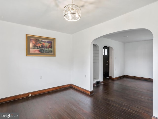 spare room featuring a chandelier and dark hardwood / wood-style flooring