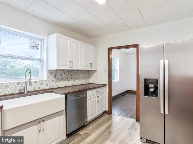 kitchen featuring appliances with stainless steel finishes, plenty of natural light, and white cabinets