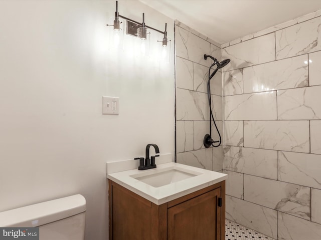 bathroom with vanity, toilet, and a tile shower