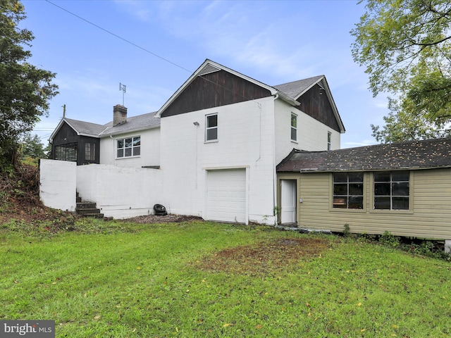 back of property featuring a garage and a lawn