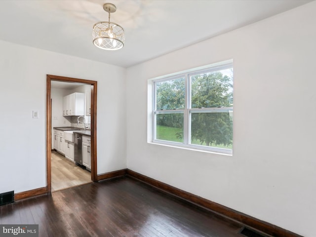 unfurnished room with a notable chandelier and hardwood / wood-style flooring