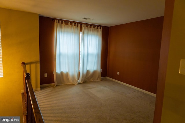 carpeted spare room with visible vents and baseboards