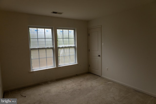 carpeted spare room with visible vents and baseboards