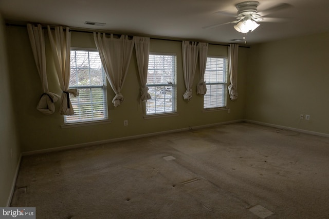 spare room featuring carpet floors, a wealth of natural light, and baseboards