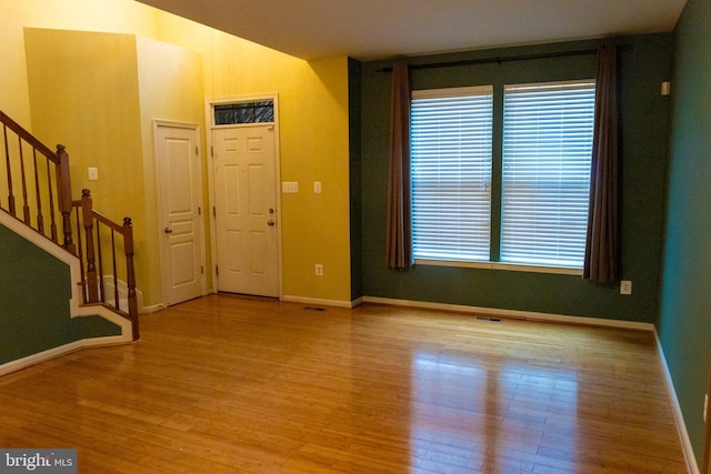 foyer featuring baseboards, stairway, and wood finished floors