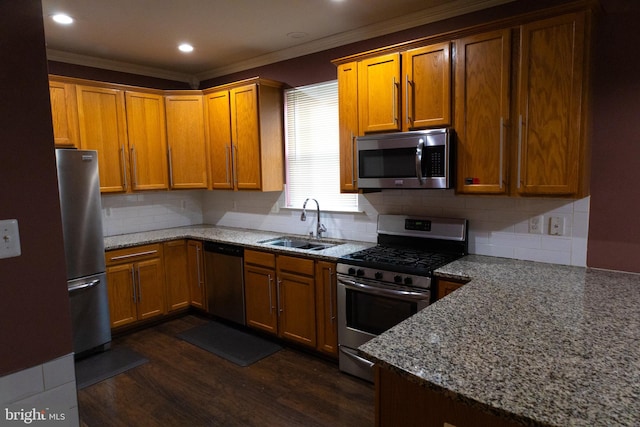 kitchen with dark wood finished floors, stainless steel appliances, tasteful backsplash, ornamental molding, and a sink