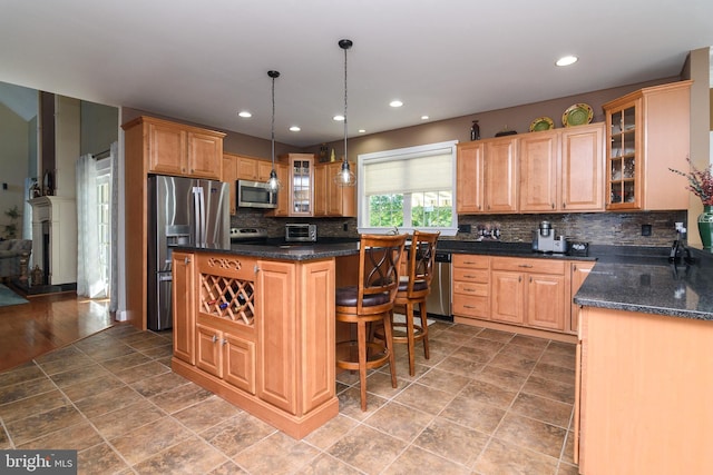 kitchen featuring a breakfast bar area, a kitchen island, decorative backsplash, hanging light fixtures, and appliances with stainless steel finishes