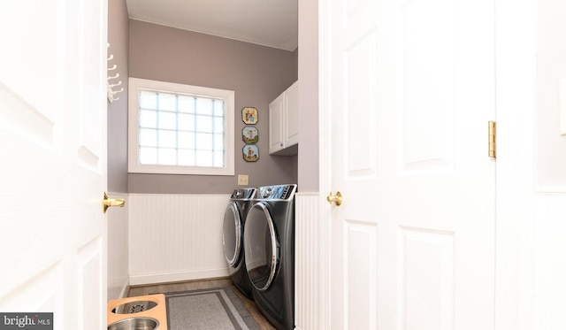 washroom featuring independent washer and dryer, hardwood / wood-style floors, and cabinets