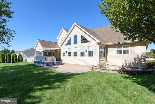 back of property with a deck, a lawn, and a patio