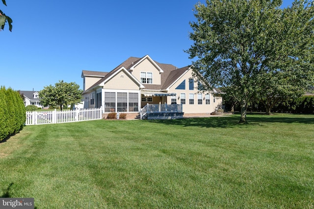 back of house featuring a sunroom and a lawn