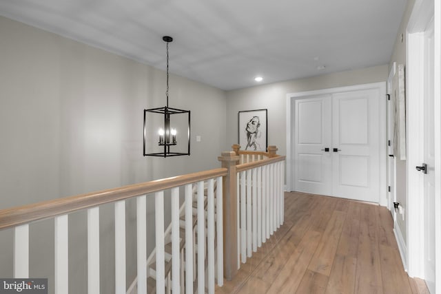 hall with light wood-type flooring and a chandelier