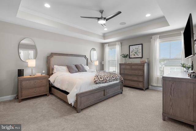 bedroom featuring ornamental molding, a tray ceiling, ceiling fan, and light colored carpet