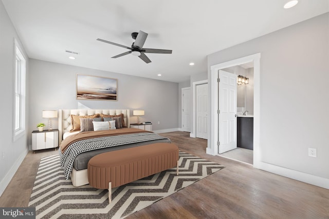 bedroom with ceiling fan, light wood-type flooring, ensuite bathroom, and multiple windows