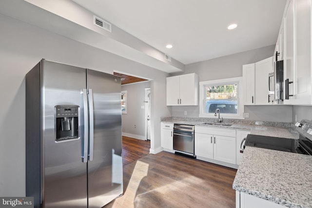 kitchen with sink, stainless steel appliances, white cabinetry, and light stone counters