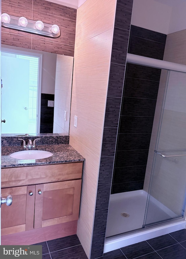 bathroom with vanity, walk in shower, tile patterned floors, and tile walls