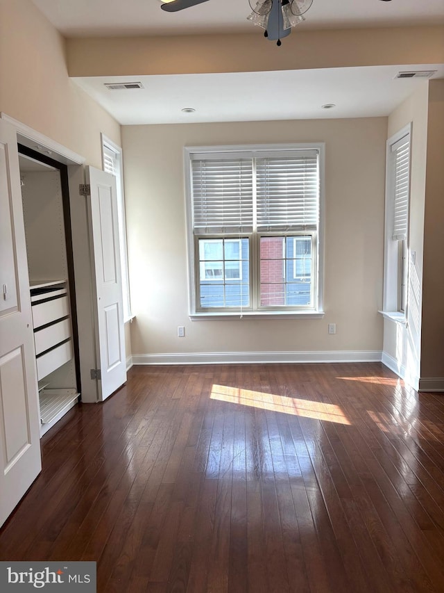 empty room with ceiling fan and dark hardwood / wood-style flooring